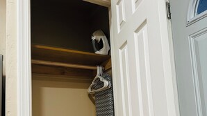 Een open kast met een hangende kledingstuk en een deur met een zilveren handgreep.