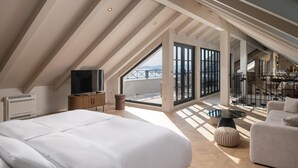 Et rummeligt loftværelse med en stor seng, et fjernsyn og en balkon med udsigt.