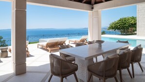 En udendørs terrasse med pool, liggestole og et bord.