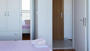 A bedroom with a bed, a wardrobe, and a door leading to another room. - Gorgeous apartment in Podgora with WiFi (Podgora)
