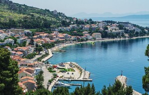 Eine Küstenstadt mit einer Marina, Häusern mit roten Ziegeldächern und freiem Blick auf das Meer.