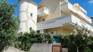 Un edificio de varios pisos con balcones, fachada de piedra y un jardín.