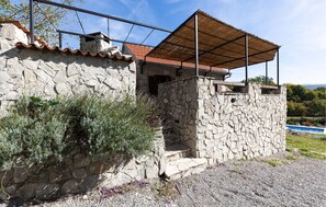 A stone house with a tiled roof, a covered porch, and a gravel driveway. - Amazing home in Donji Bitelic (Donji Bitelic)