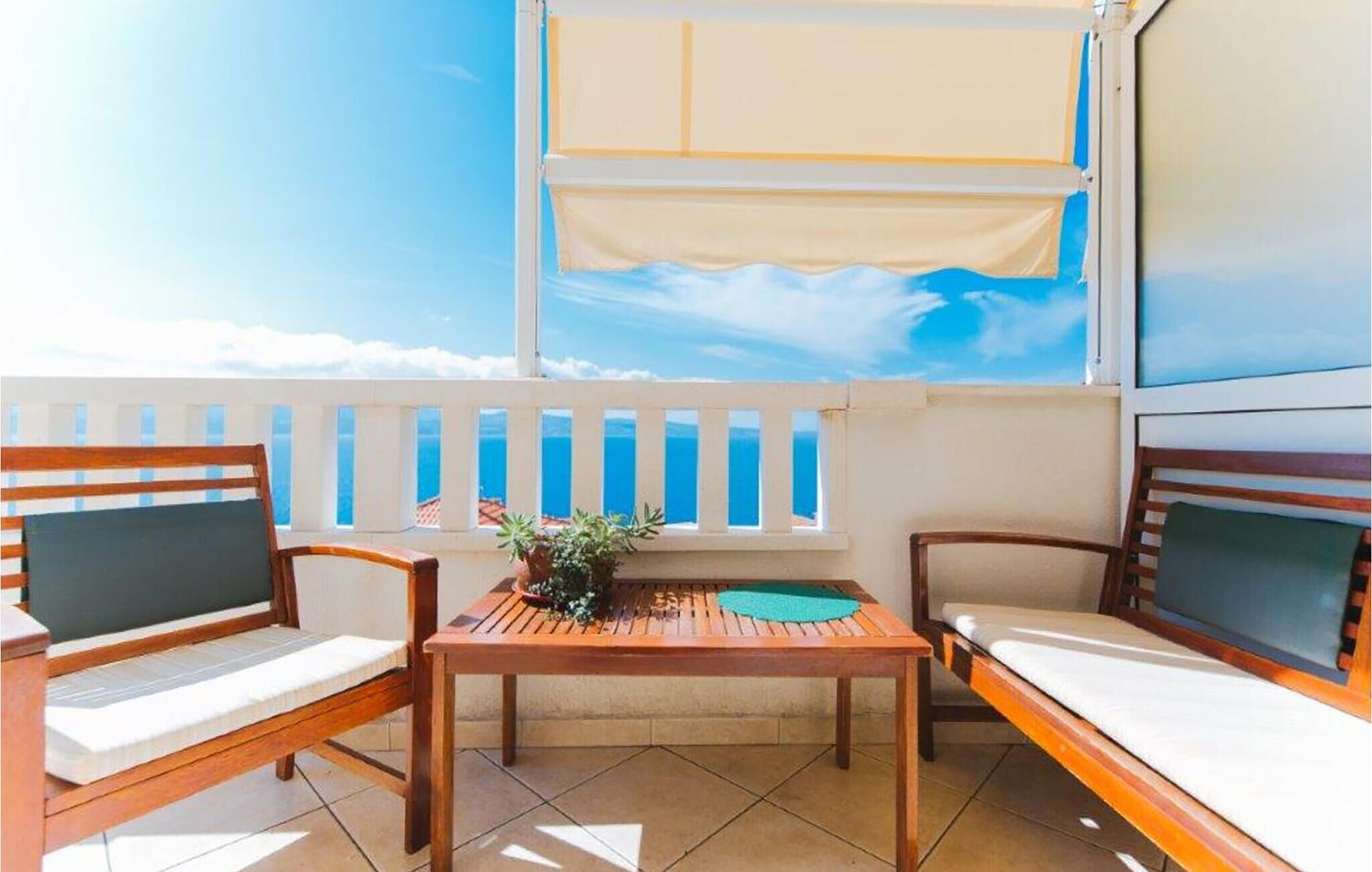 A balcony with a wooden table, two chairs, and a small potted plant.