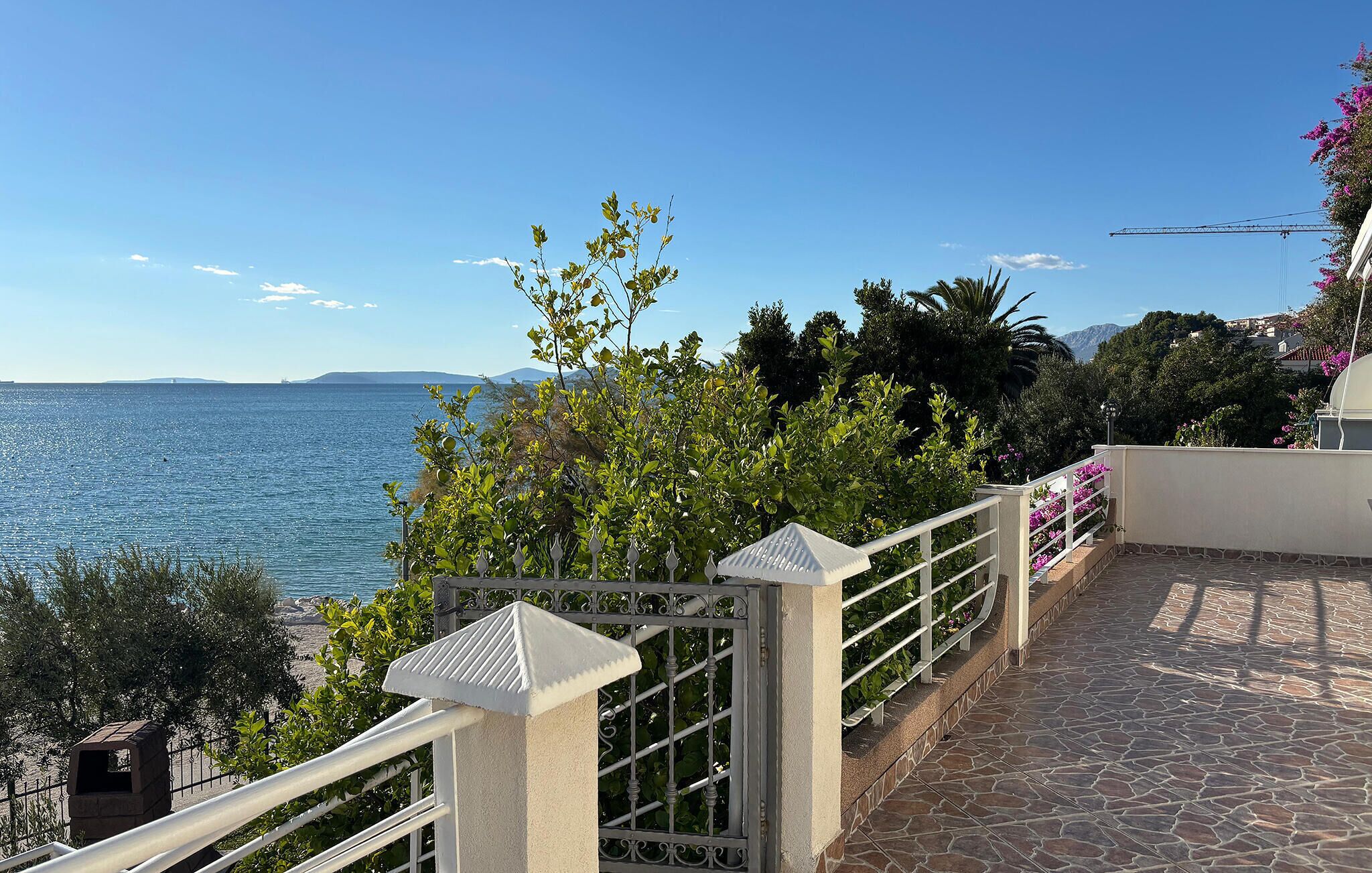Une terrasse dallée de pierres, avec une rambarde en métal, qui offre une vue sur une étendue d’eau et sur la végétation environnante.