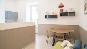 A modern kitchen with a wooden dining table and chairs, a built-in bench, and a hanging pendant light. - Dimora Merliani (Naples)