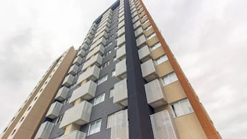 Edifício residencial alto com várias varandas, design arquitetônico moderno e um logotipo visível.