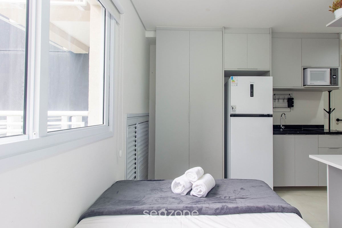 Una habitación pequeña con cama, una kitchenette y una ventana.