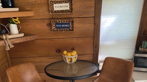 A wooden interior with two brown leather chairs around a glass table with a bowl of lemons. - Blue Spirit · Private Studio Cabin in the Trees (Caddo Gap)