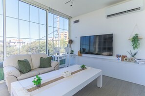 Departamento, 2 habitaciones, cocineta, vista a la ciudad | Sala de estar | Smart TV de 65 pulgadas con canales por cable y servicios de streaming 