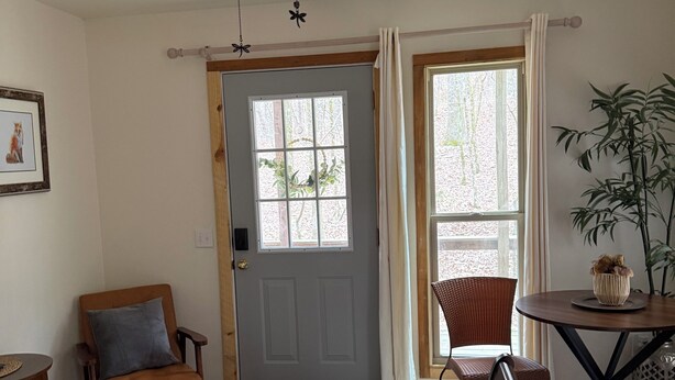 Une pièce comprenant un lit, une chaise, une table, un ventilateur de plafond, une porte et une fenêtre.