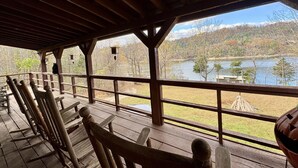 Una terraza de madera con bancos que da a un lago y bosque.
