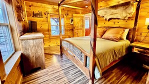 Un dormitorio tipo cabaña de madera con una cama con dosel, paredes de madera y una alfombra de piel.