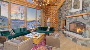 A log cabin interior with a stone fireplace, large windows, and a cozy seating area. - The Wilson Vista: Epic Space & Solitude (Mountain Village)