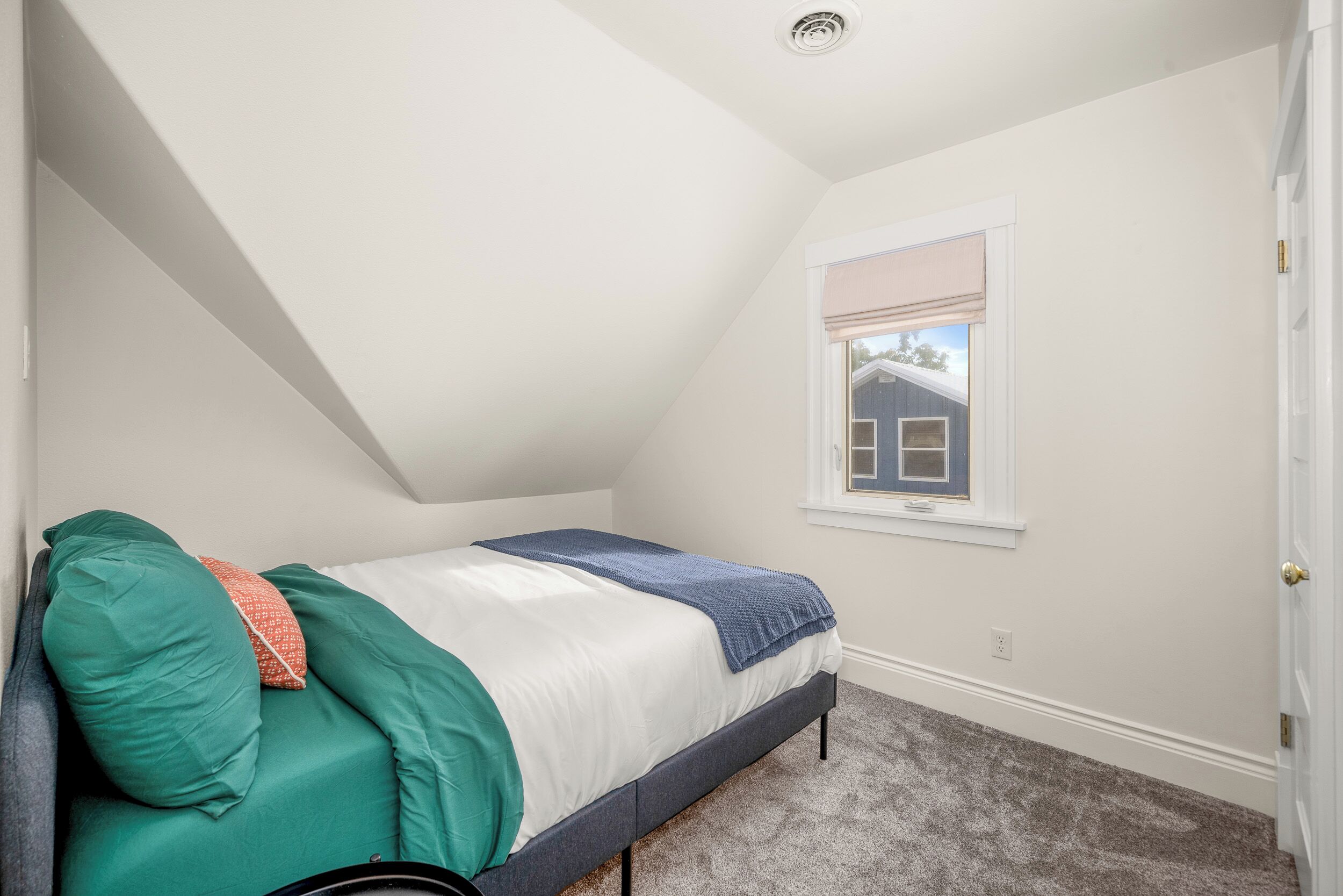 A bedroom with a bed, a window, and a door.