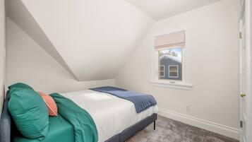 A bedroom with a bed, a window, and a door.