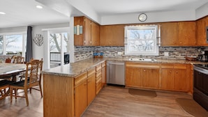 A modern kitchen with wooden cabinets, granite countertops, and a dishwasher. - Lakefront Retreat w/ Dock + Games (Madison Lake)