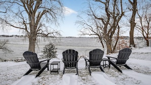 Three Adirondack chairs facing a snowy landscape with bare trees and a view of a distant field. - Lakefront Retreat w/ Dock + Games (Madison Lake)