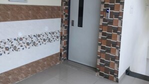 A hallway with a patterned wall, a door, and a light switch on the wall. - VIJETHA GRAND LODGE  (Mangalagiri)