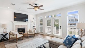 A spacious living room with a fireplace, comfortable seating, a flat-screen TV, and large windows. - Private Pool, LSV/Golf Cart, Bikes, & Pet Friendly! 1/2 MILE TO BLUE MOUNTAIN BEACH! (Santa Rosa Beach)