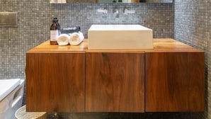 Un baño moderno con un espejo grande, tocador de madera y piso de baldosas.