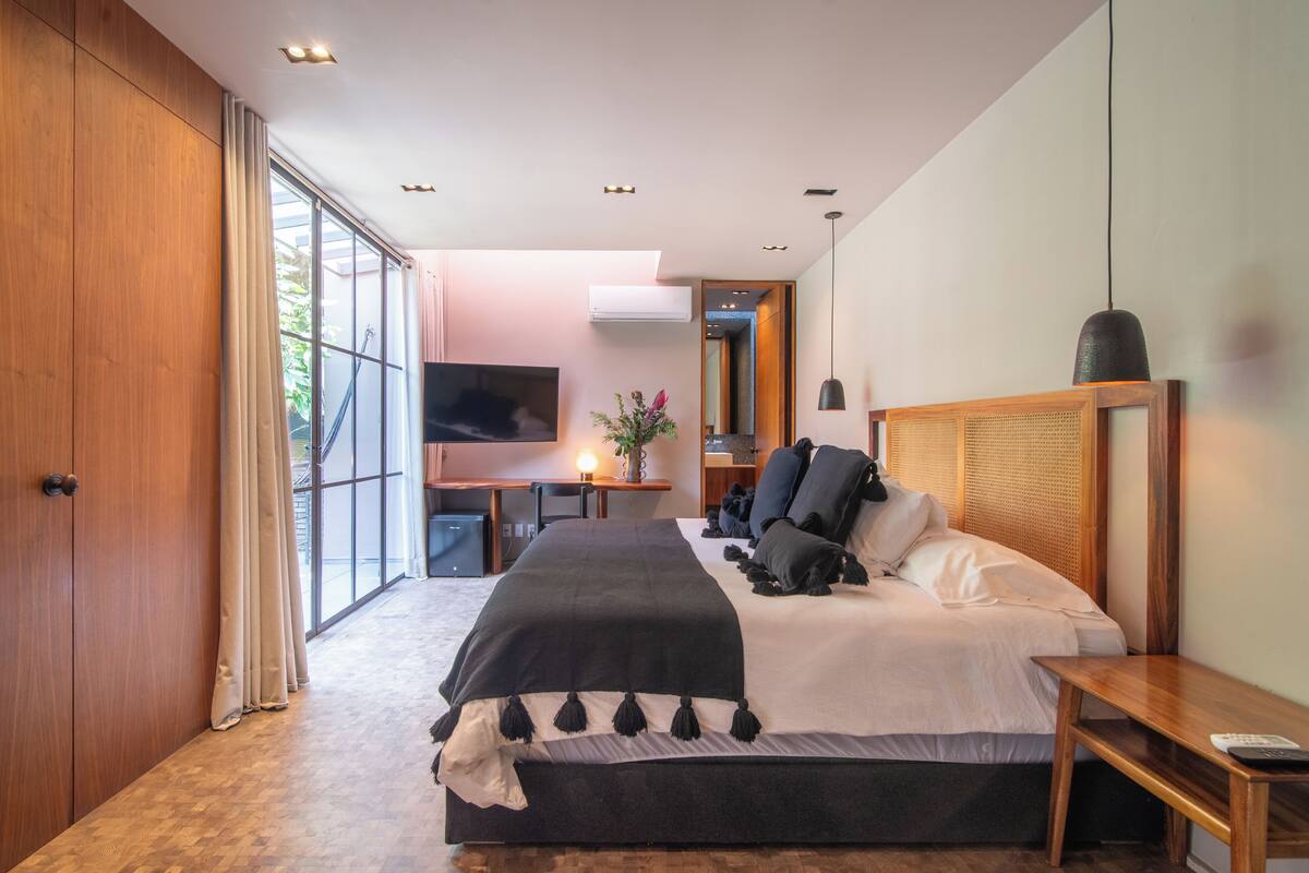 A modern bedroom with a large bed, a desk, and a TV.