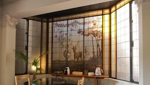 Un comedor con una mesa redonda, seis sillas, un separador decorativo con una pintura de un ciervo y una planta en maceta.