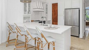 Una cucina moderna con un'isola grande, mobili bianchi e un frigorifero in acciaio inossidabile.
