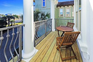 A balcony with a wooden table and chairs, white columns, and a metal railing. - Steps to Beach! Private Pool, 6-Seater LSV/golf cart, & 4 Bikes Included! Sleeps 18! (Santa Rosa Beach)