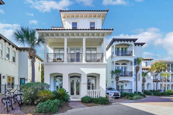 A two-story building with a balcony, a driveway, and a palm tree. - Steps to Beach! Private Pool, 6-Seater LSV/golf cart, & 4 Bikes Included! Sleeps 18! (Santa Rosa Beach)