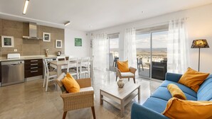 A modern living room with a sofa, chairs, a coffee table, and a view of the city through large windows.
