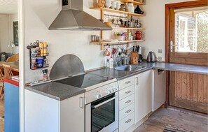 A compact kitchen with a built-in oven, a stainless steel range hood, and wooden shelves above the counter. - Awesome home in Melby with WiFi (Melby)