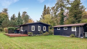 Een chalet met twee verdiepingen, een terras en een klein zitgedeelte buiten.