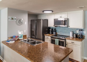 A modern kitchen with granite countertops, stainless steel appliances, and white cabinetry. - Charming Home Minutes from Parks (Kissimmee)