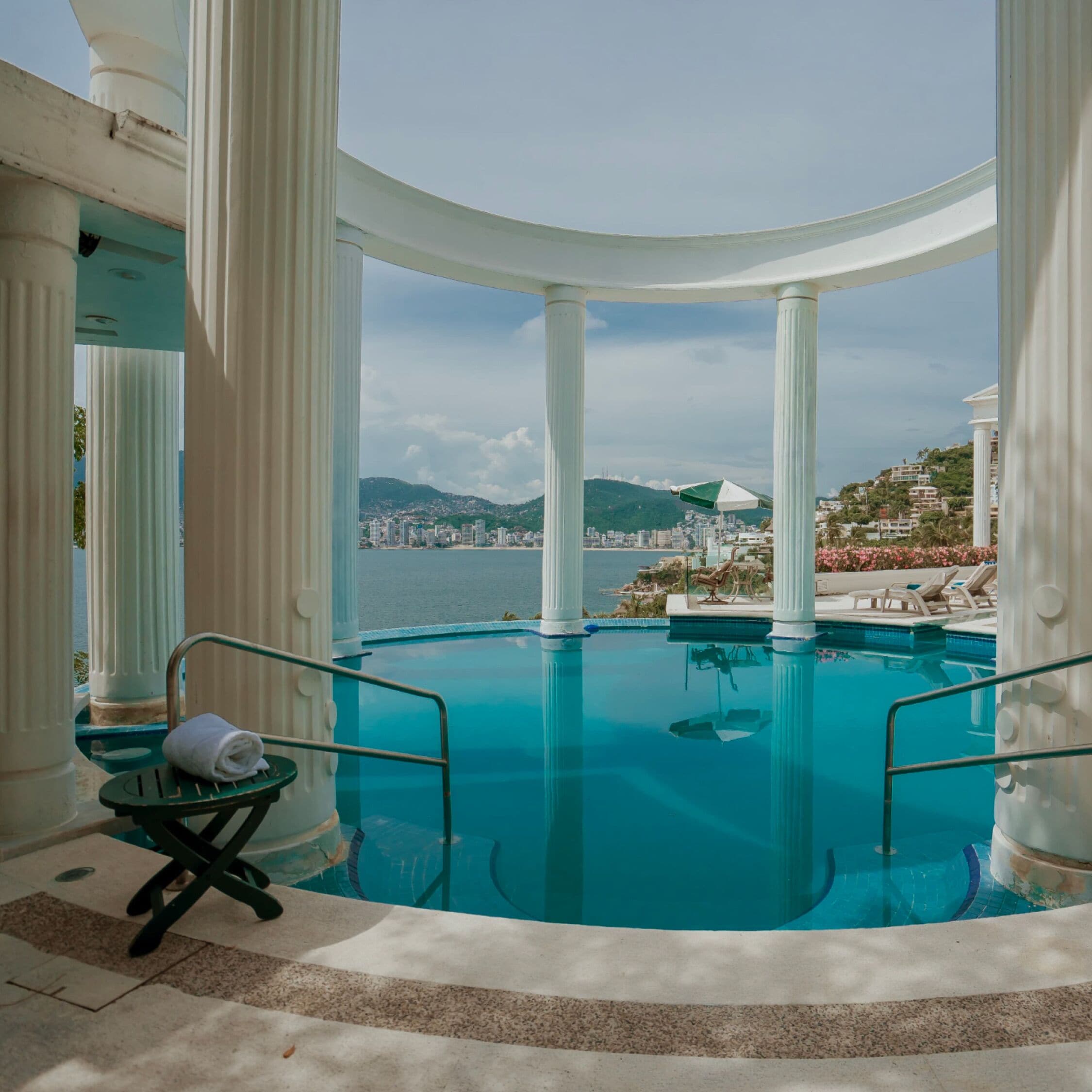 Una piscina al aire libre, sombrillas, sillones reclinables de piscina