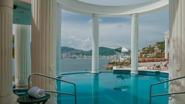 Área da piscina com vista para a paisagem urbana e montanhas.