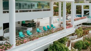 Uma área de estar ao ar livre com vários níveis, piso xadrez, cadeiras verdes e piscina.