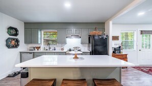 Una cocina moderna con una isla central, armarios grises y un refrigerador negro.