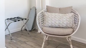 Huoneessa on rottinkituoli, seinälle ripustettu pyykkiköysi ja valkoinen vaatekaappi.