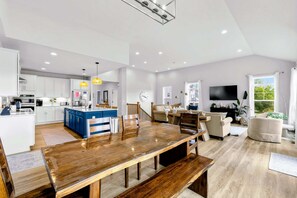 A modern kitchen with white cabinets, a blue island, and a dining area with a wooden table and benches. - Lakefront Lake Anna, Dock, Deck, Views, Games (Mineral)