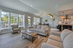 A spacious living room with a large window, a sofa, a coffee table, and a kitchen area with a dining table. - Lakefront Lake Anna, Dock, Deck, Views, Games (Mineral)