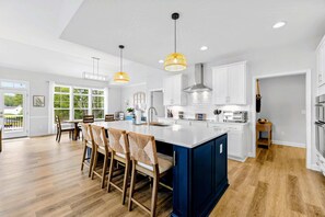 A modern kitchen with a central island, white cabinetry, and a blue accent wall. - Lakefront Lake Anna, Dock, Deck, Views, Games (Mineral)