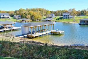 A lakeside property with multiple docked boats, a covered pavilion, and several houses in the background. - Lakefront Lake Anna, Dock, Deck, Views, Games (Mineral)