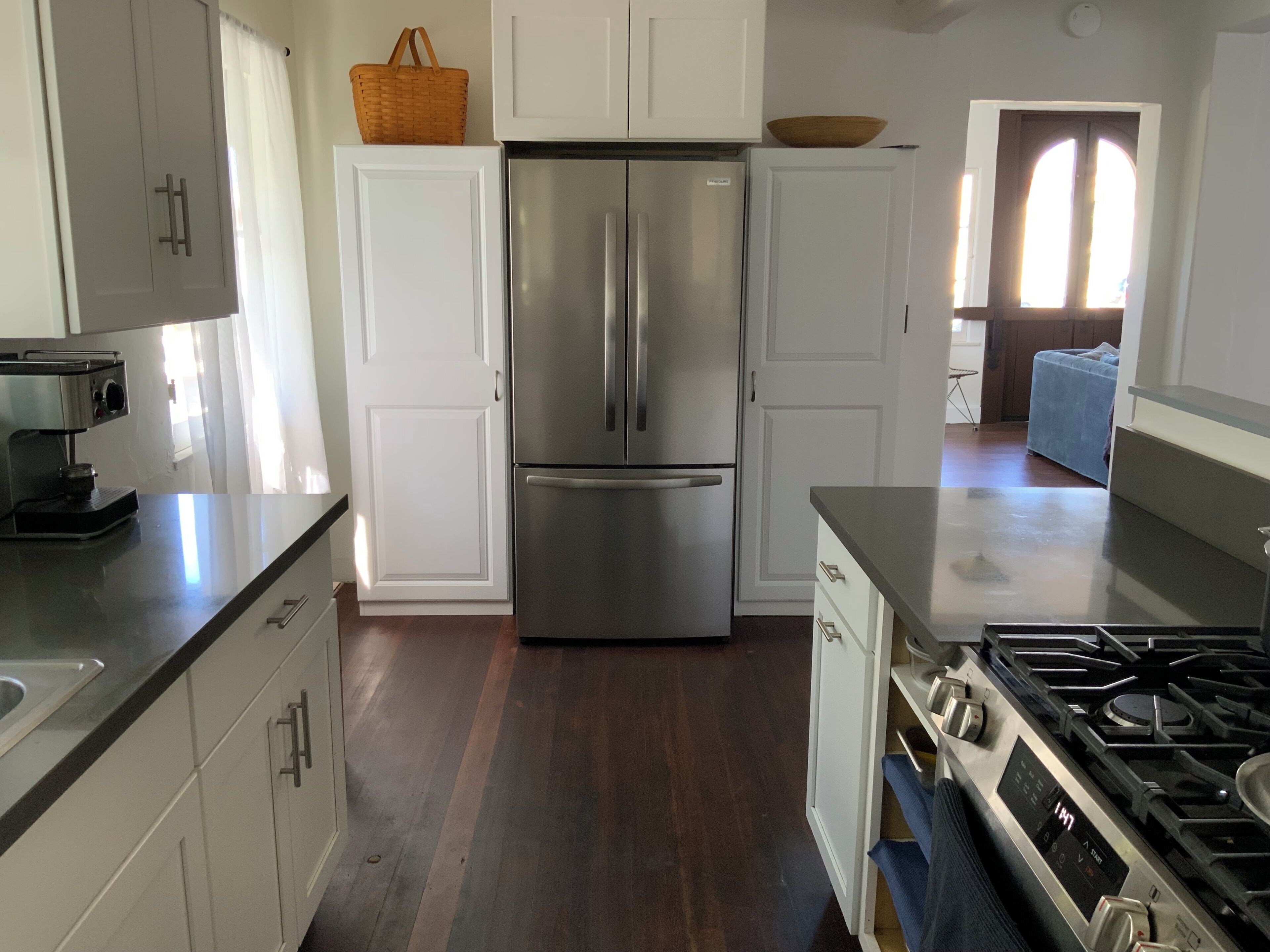 A modern kitchen with white cabinetry, a stainless steel refrigerator, a gas stove, and a coffee maker.