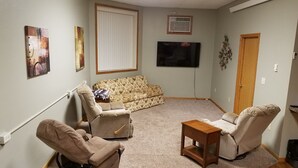 A living room with a sofa, two armchairs, a coffee table, and a flat-screen TV.