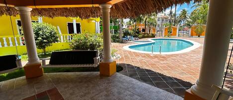 A covered outdoor area with a pool, columns, and a checkered floor.