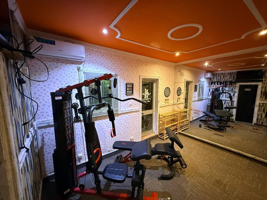 Academia com equipamentos de ginástica, espelho e parede estampada.