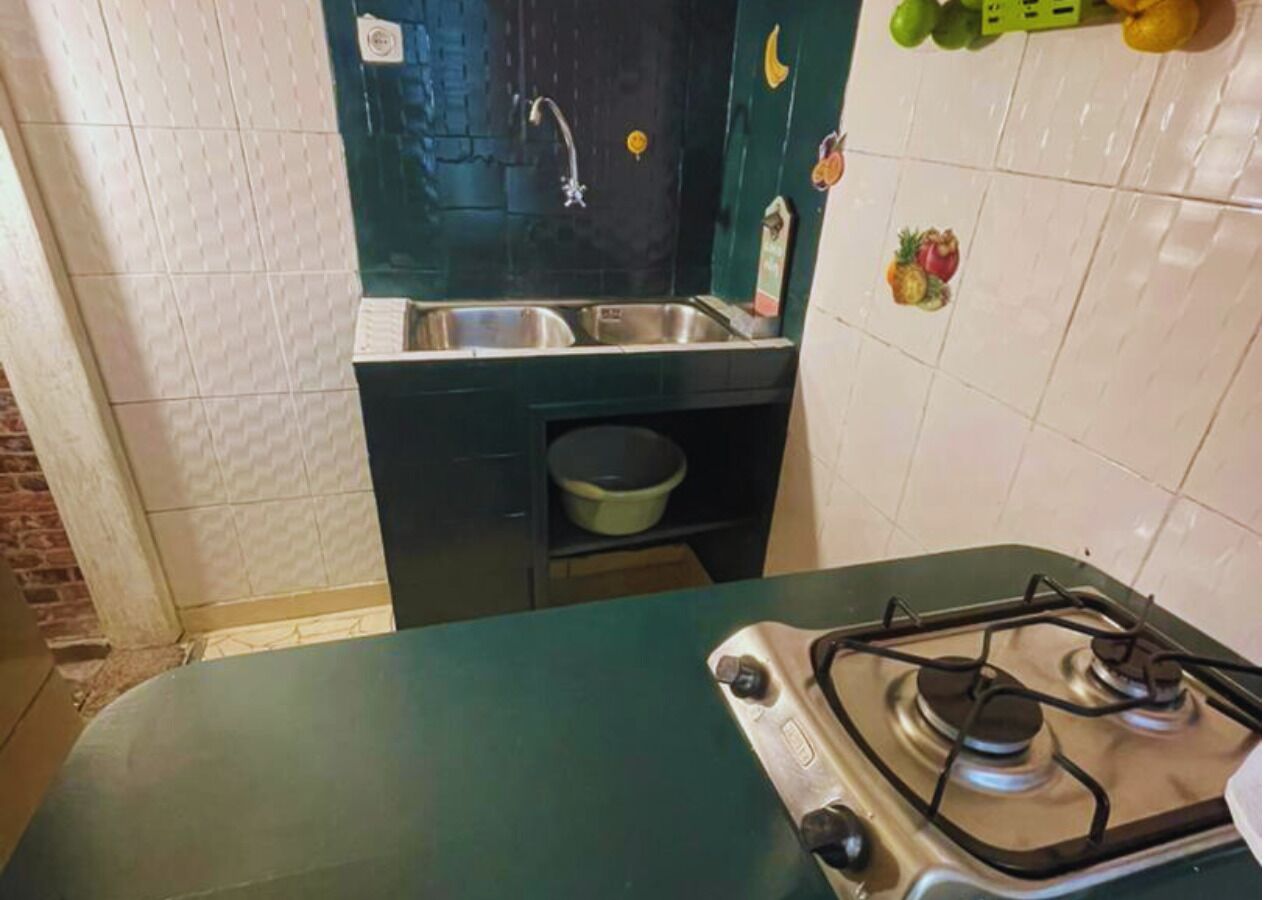 Uma cozinha com fogão a gás, pia e uma bancada pequena.