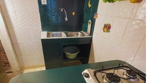 Una cocina con estufa a gas, pileta y una pequeña mesada.