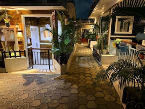 A narrow alleyway with tiled flooring, potted plants, and a wooden fence. - Appartement Millenium (Yaoundé)